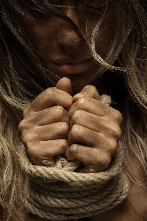 a woman’s hands tied with rope