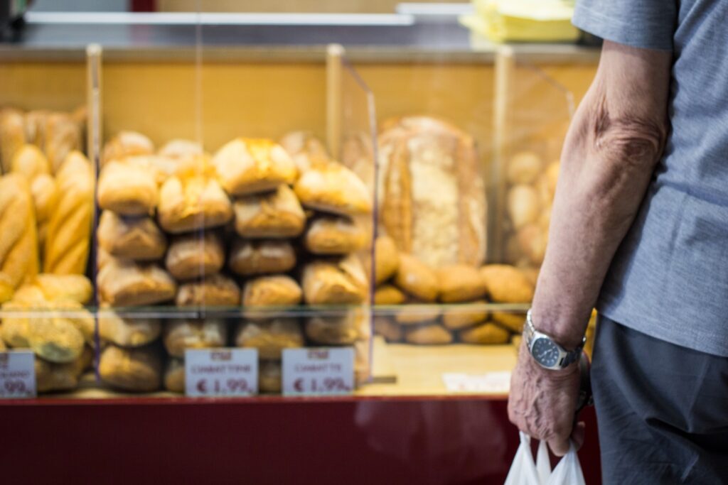 An old man buying bread from a SNAP retailer