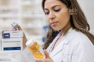Female pharmacist reads label on medication bottle