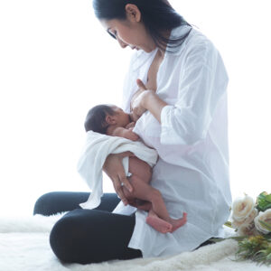 Hatchery_Young Asian mother breastfeeding baby in her arms on bed at home, 2 week old baby, newborn baby concept