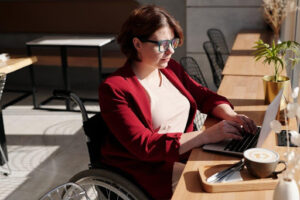 woman learning online on laptop sitting in a café in a wheelchair