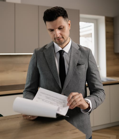 A man in a grey suit jacket looking at documents