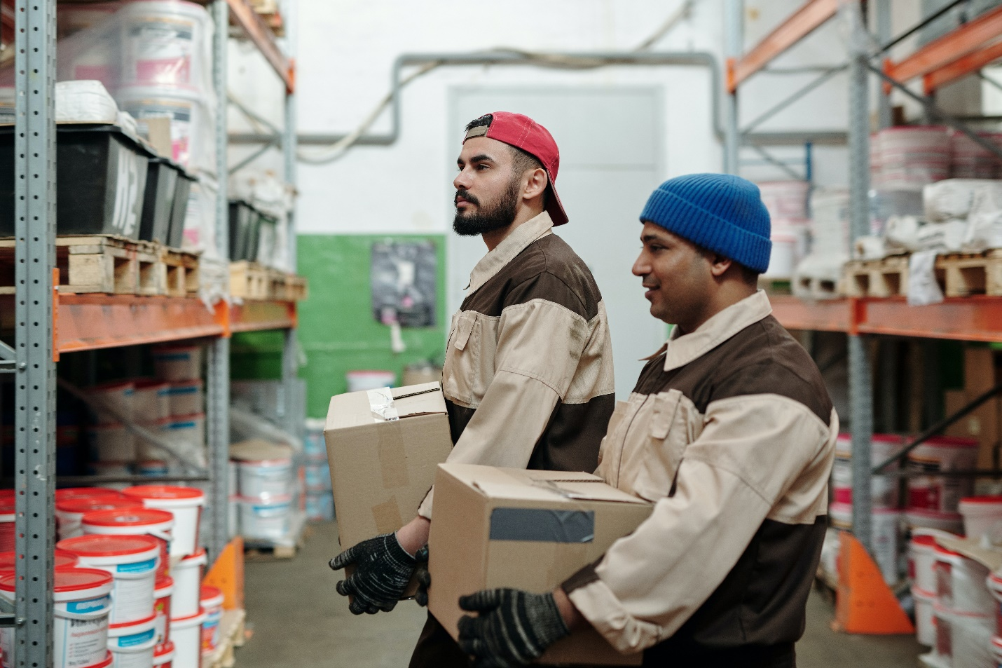 two workers holding two cardboard boxes in a warehouse