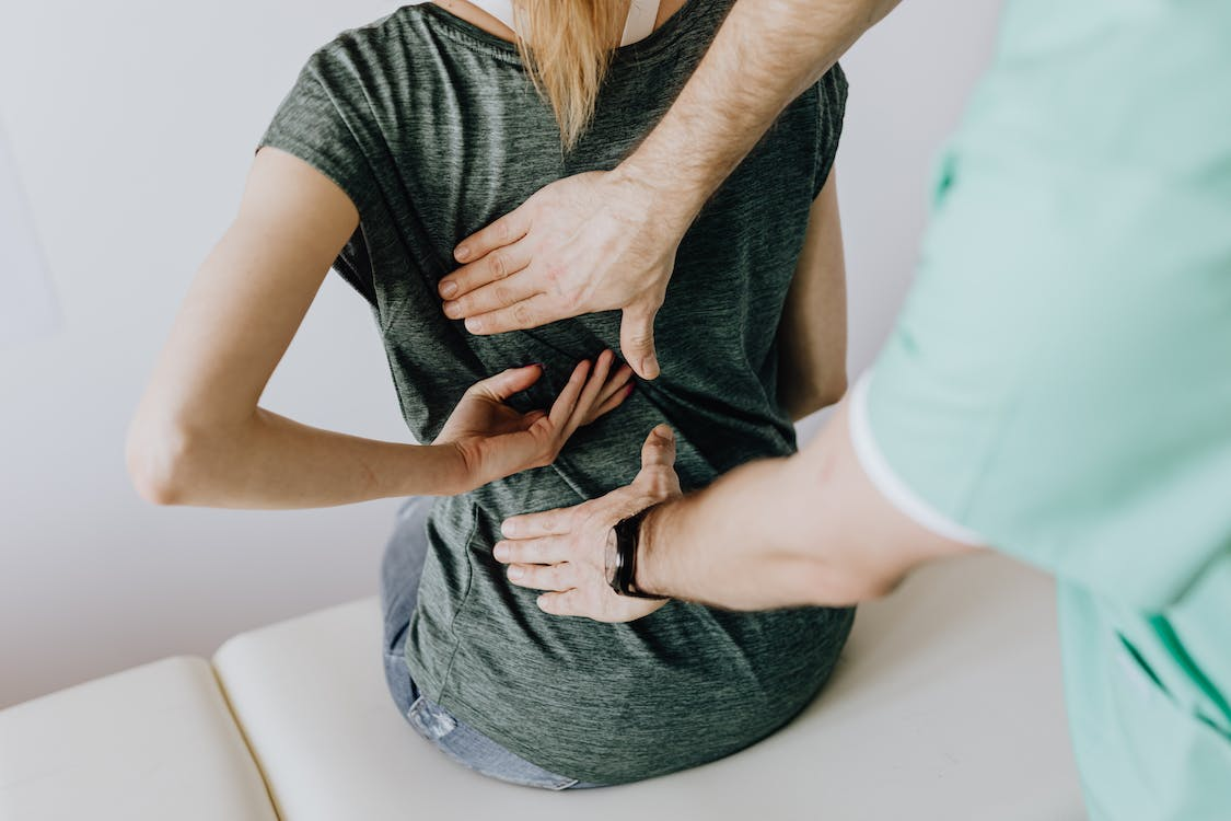 Person examining a patient with back pain