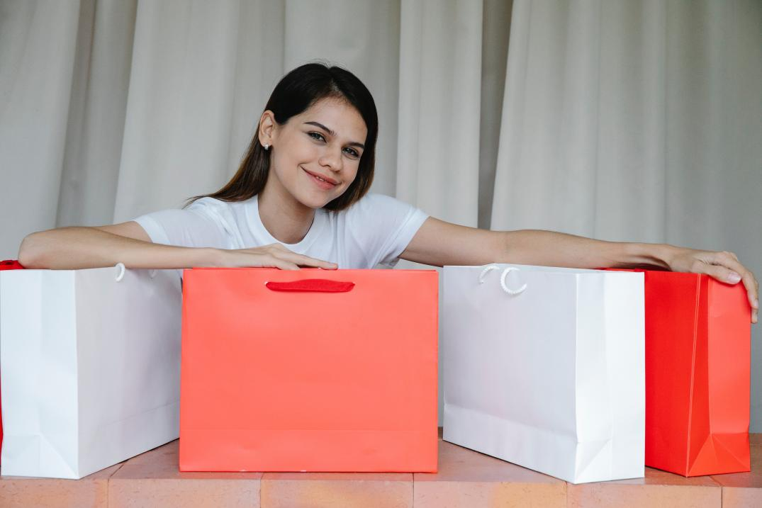 A Happy girl sitting with red and white paper bags