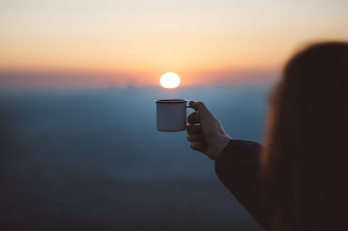 a person holding a cup of warm coffee