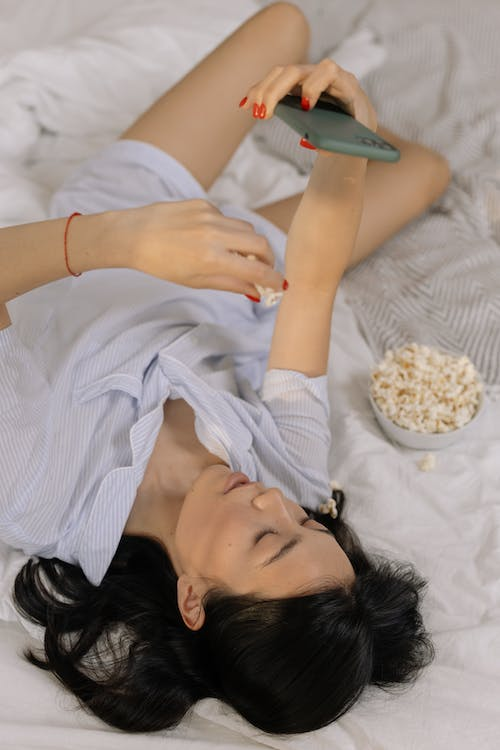  a woman using her phone and eating popcorn