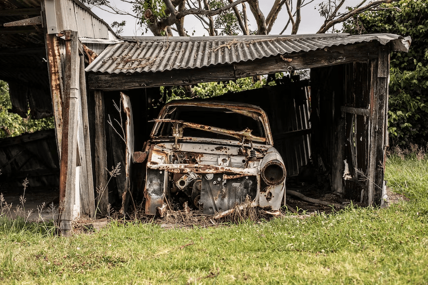 A junk car in a broken-down shed