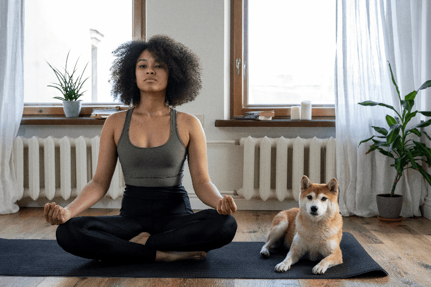 A person doing yoga beside their dog.