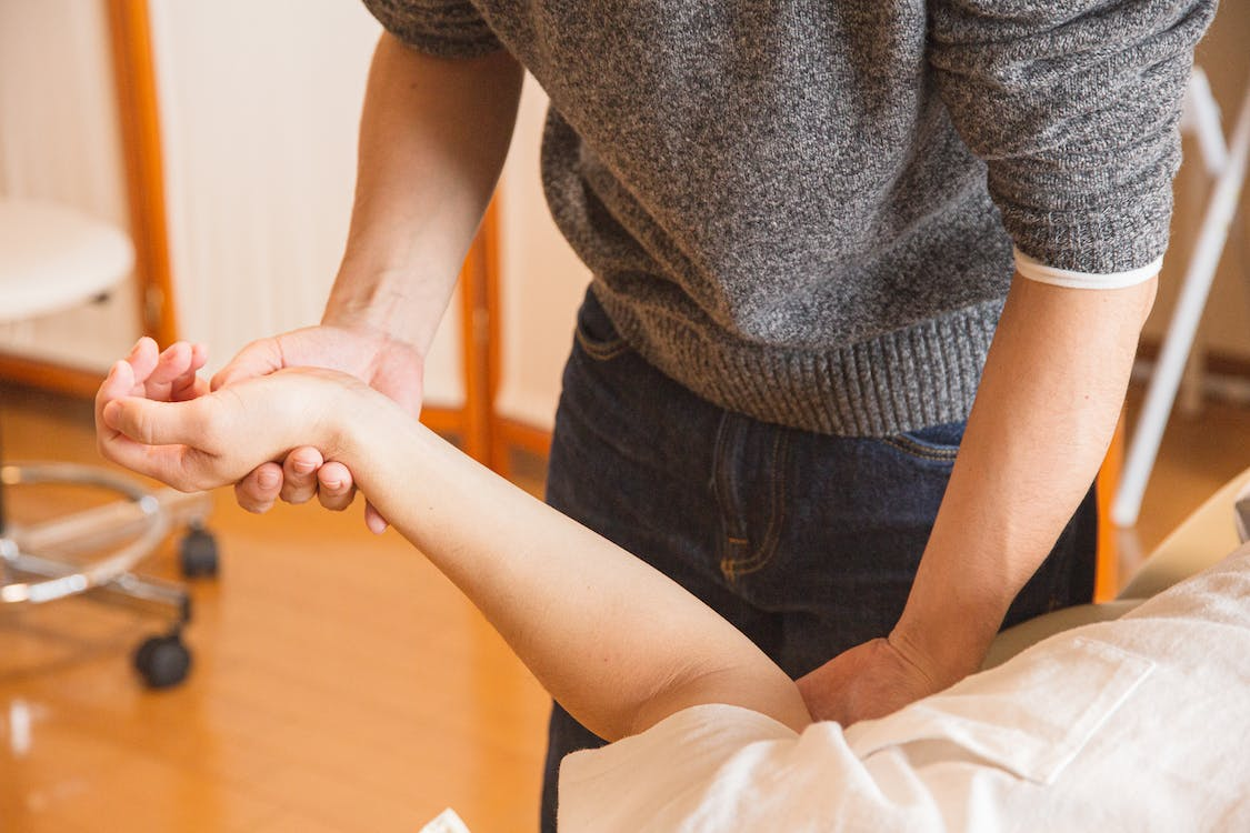 A massage therapist giving a massage on a client’s hands