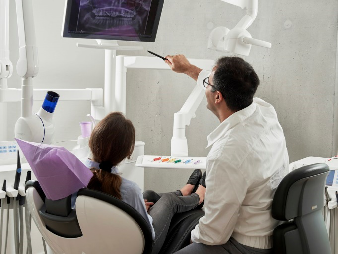 A dentist pointing towards a screen 