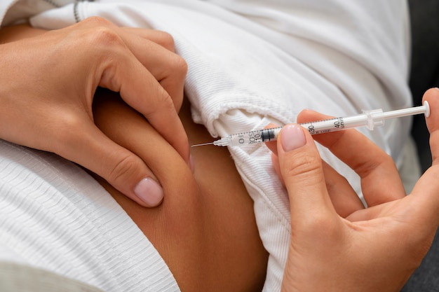 Close-up of a person administering an HCG injection into the abdomen.