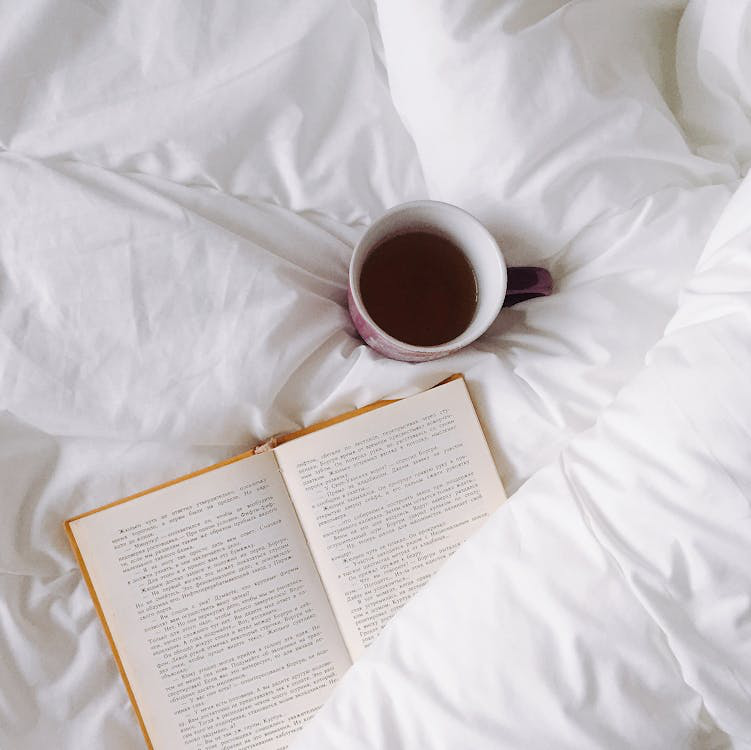 Cup of tea on a bed with a book for a relaxing evening routine