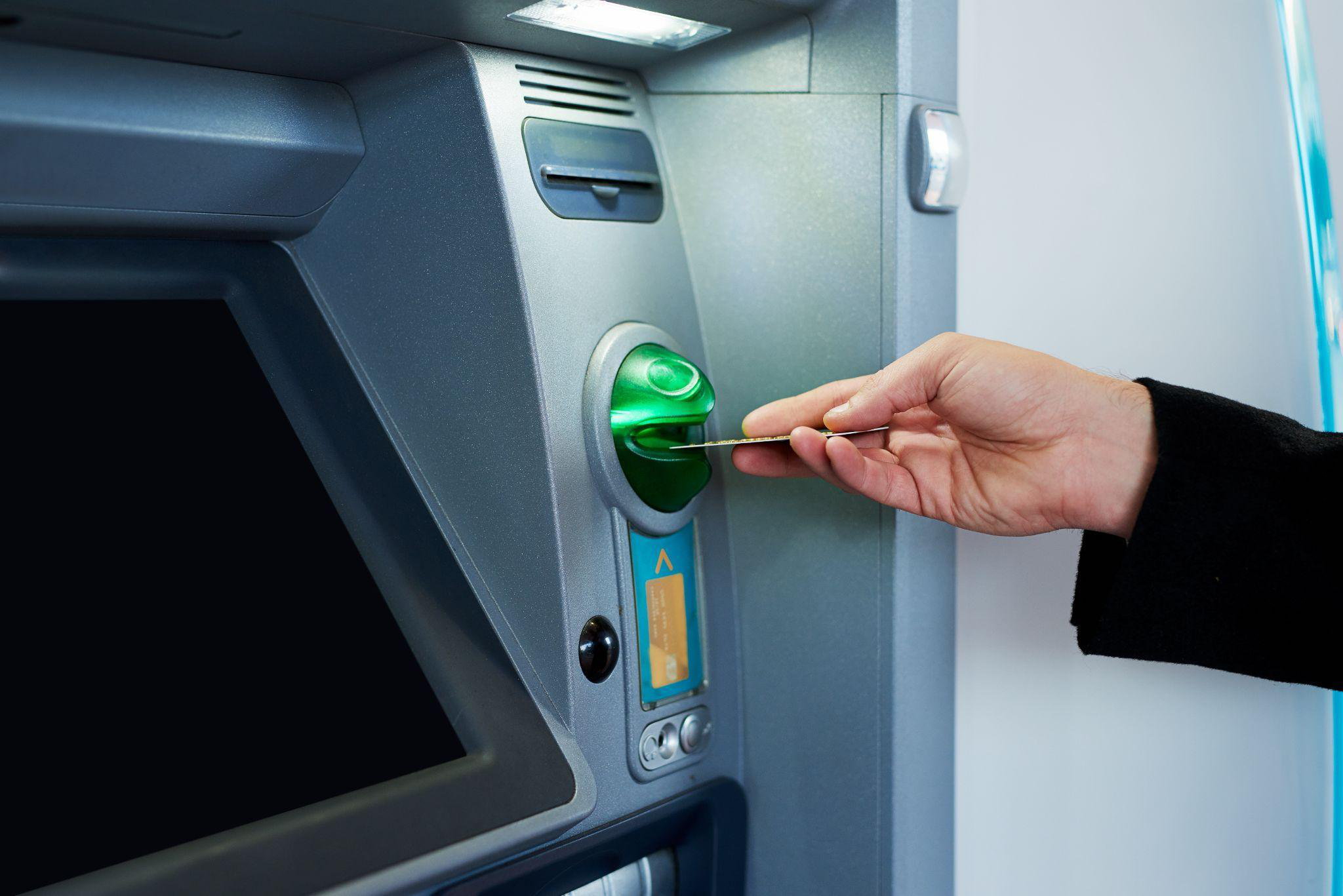 An image of a person inserting a debit card at an ATM in Washington